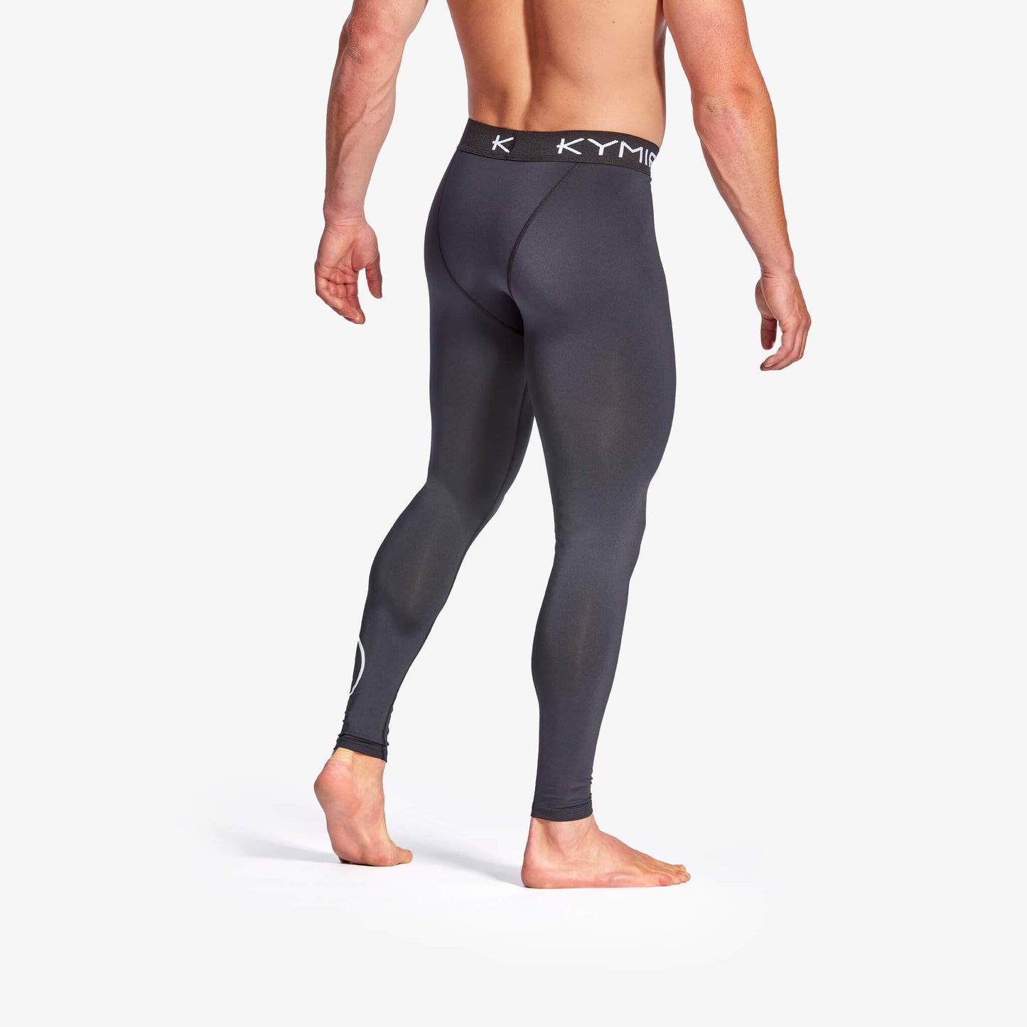 Person wearing black compression leggings with a visible brand logo on a white background
