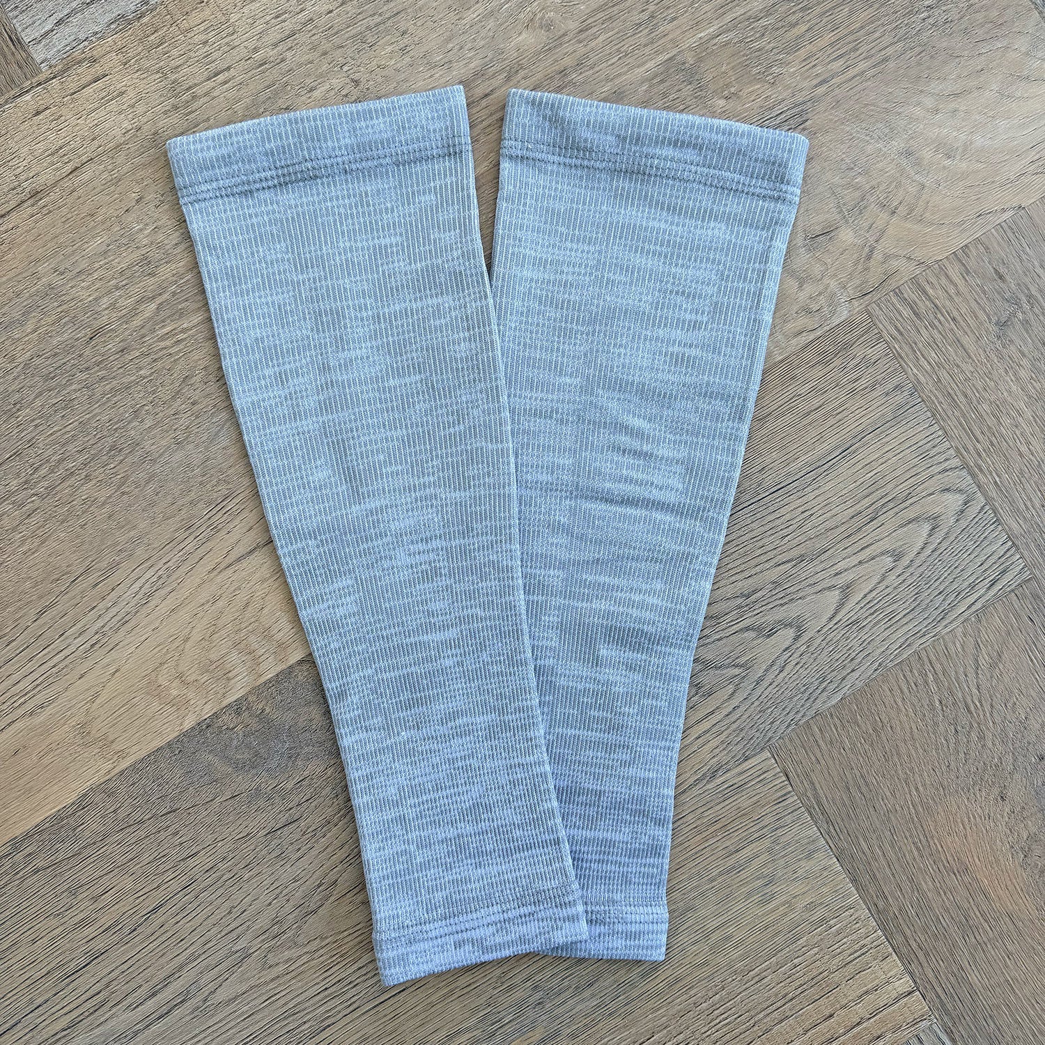 Two light blue ribbed leg warmers on a wooden floor.