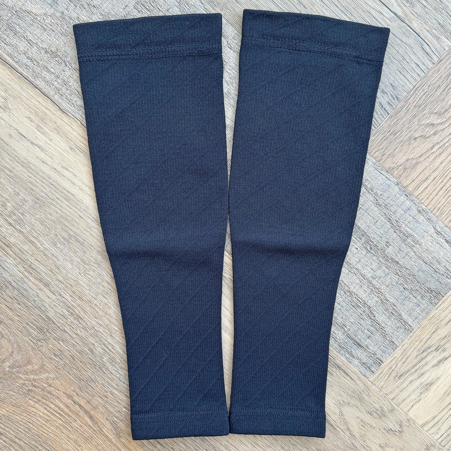 Pair of navy blue compression sleeves on a wooden floor.
