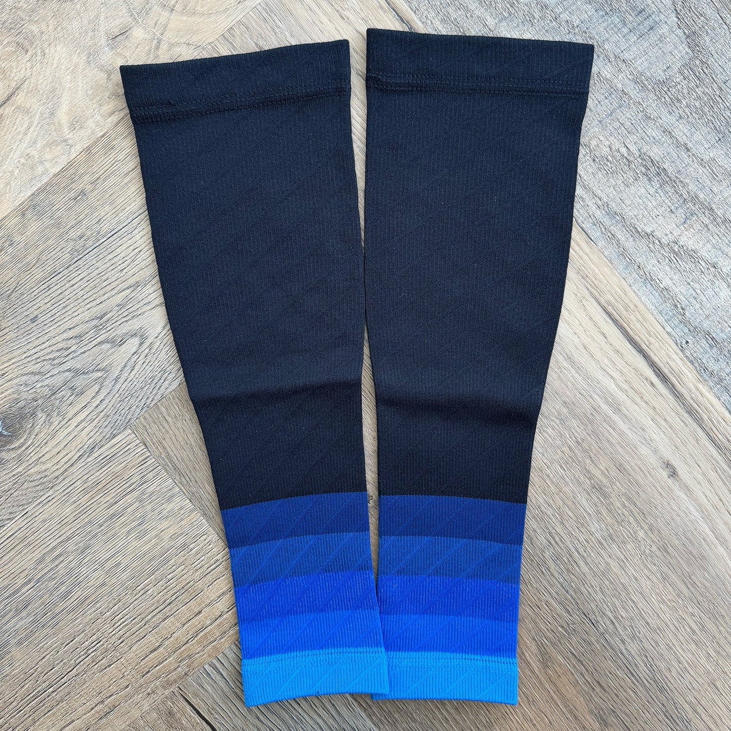 Pair of black and blue leg sleeves on a wooden surface