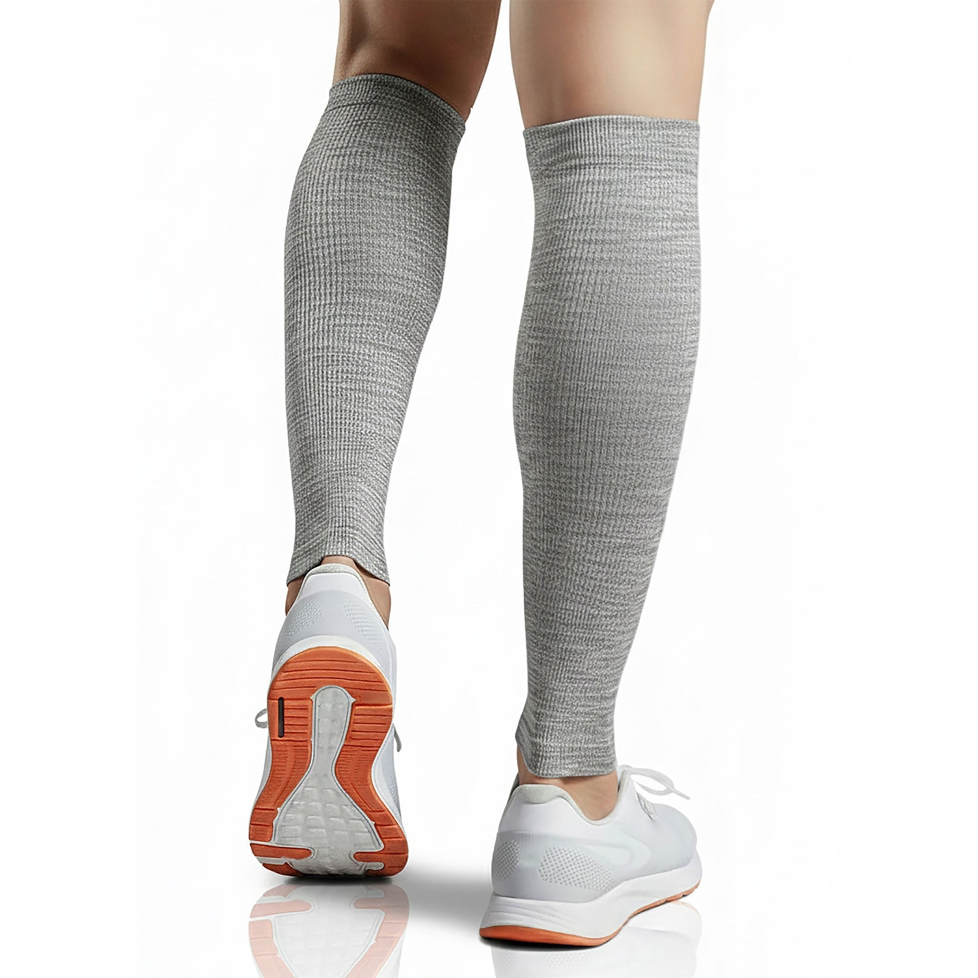 Person wearing gray knee-high socks and white sneakers with orange soles on a white background